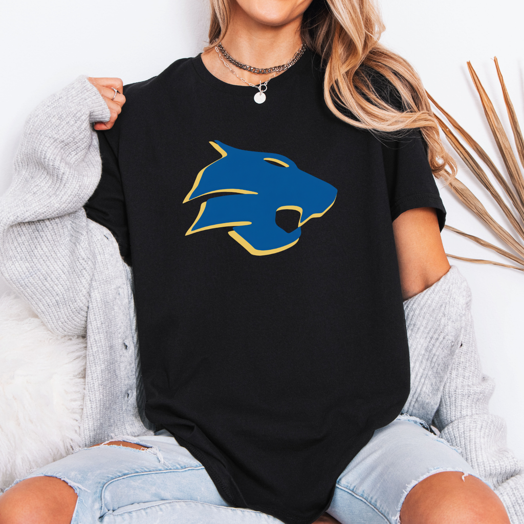 Person wearing a black t-shirt with a blue and yellow graphic design, sitting on a white surface.