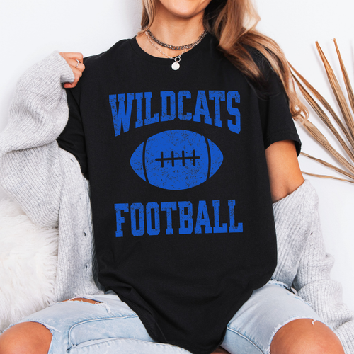 A woman wearing a  black colored t-shirt with a blue distressed graphic that reads 'WILDCATS FOOTBALL' with a football in the center.
